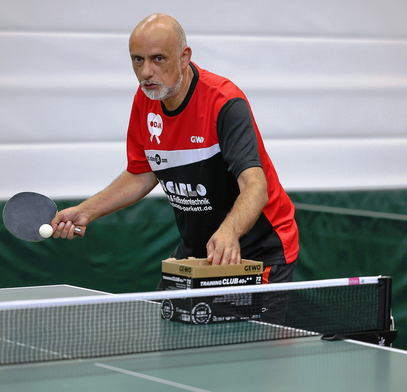 Ein Mann im mittleren Alter spielt Tischtennis.