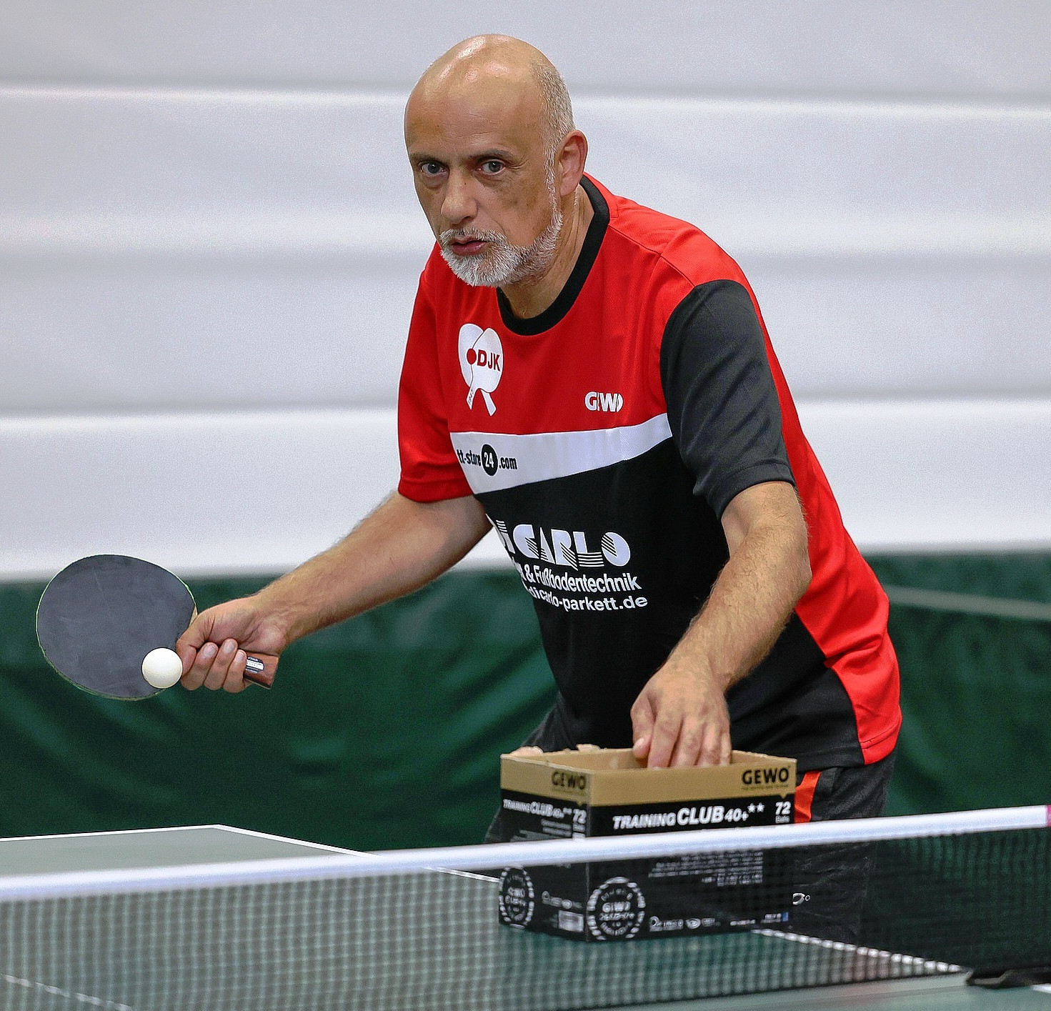 Ein Mann im mittleren Alter spielt Tischtennis.