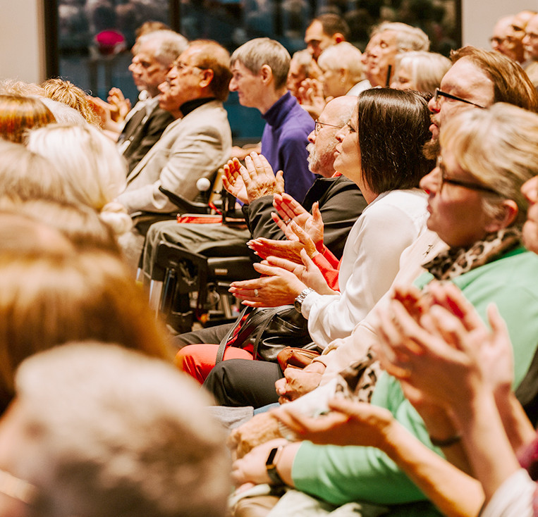 Ein Saal mit vielen Menschen, die applaudieren.