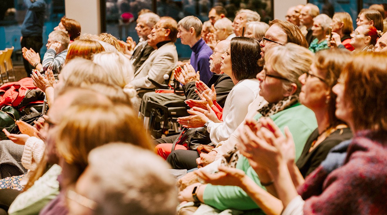 Ein Saal mit vielen Menschen, die applaudieren.