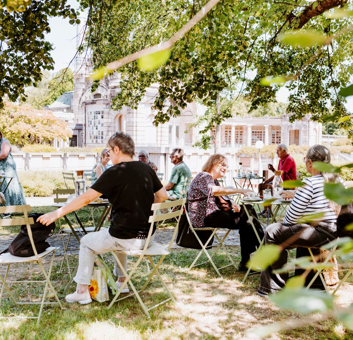 Menschen sitzen gemeinsam am Tisch mit Kaffee und Kuchen